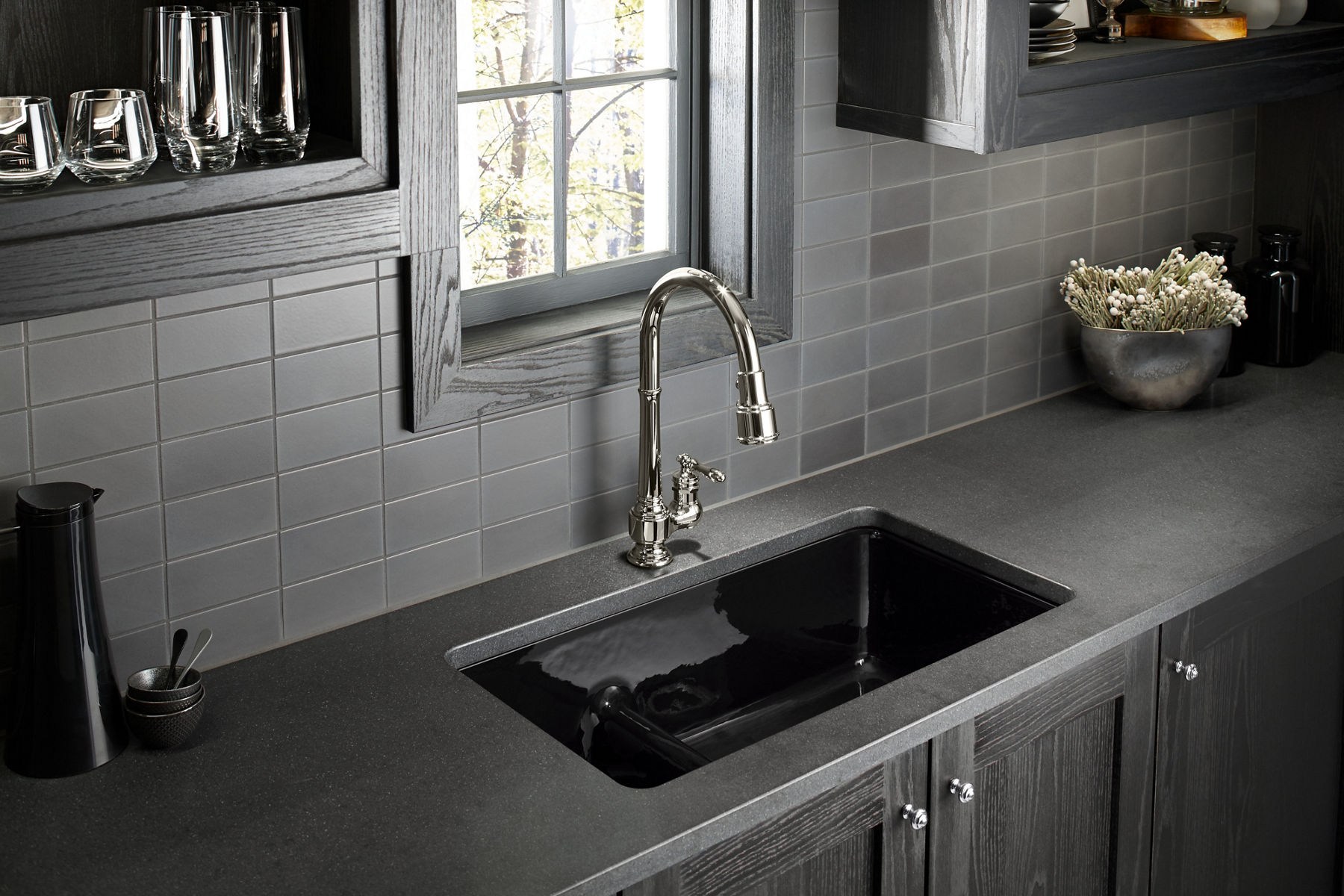A KOHLER Artifacts single-hole kitchen sink faucet and Iron/Tones Smart Divide double bowl kitchen sink installed under a window.