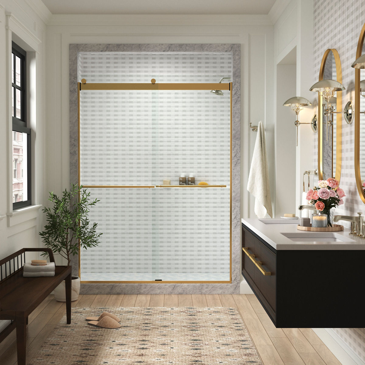 A bathroom with off-white walls, a window on the left with a small bench below it, a shower in the center with a brushed brass sliding glass door, and a wall-mounted double vanity on the right.