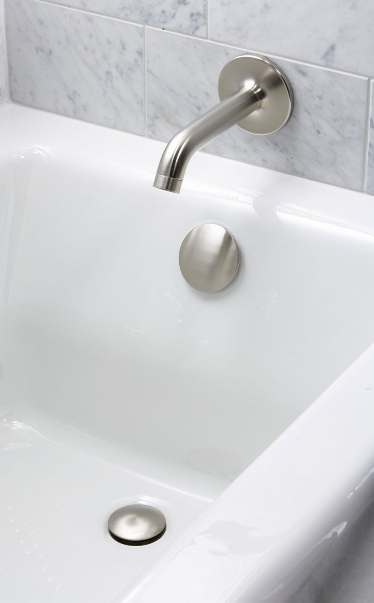 A white bathtub with brushed nickel faucet and light gray mottled stone tile walls.