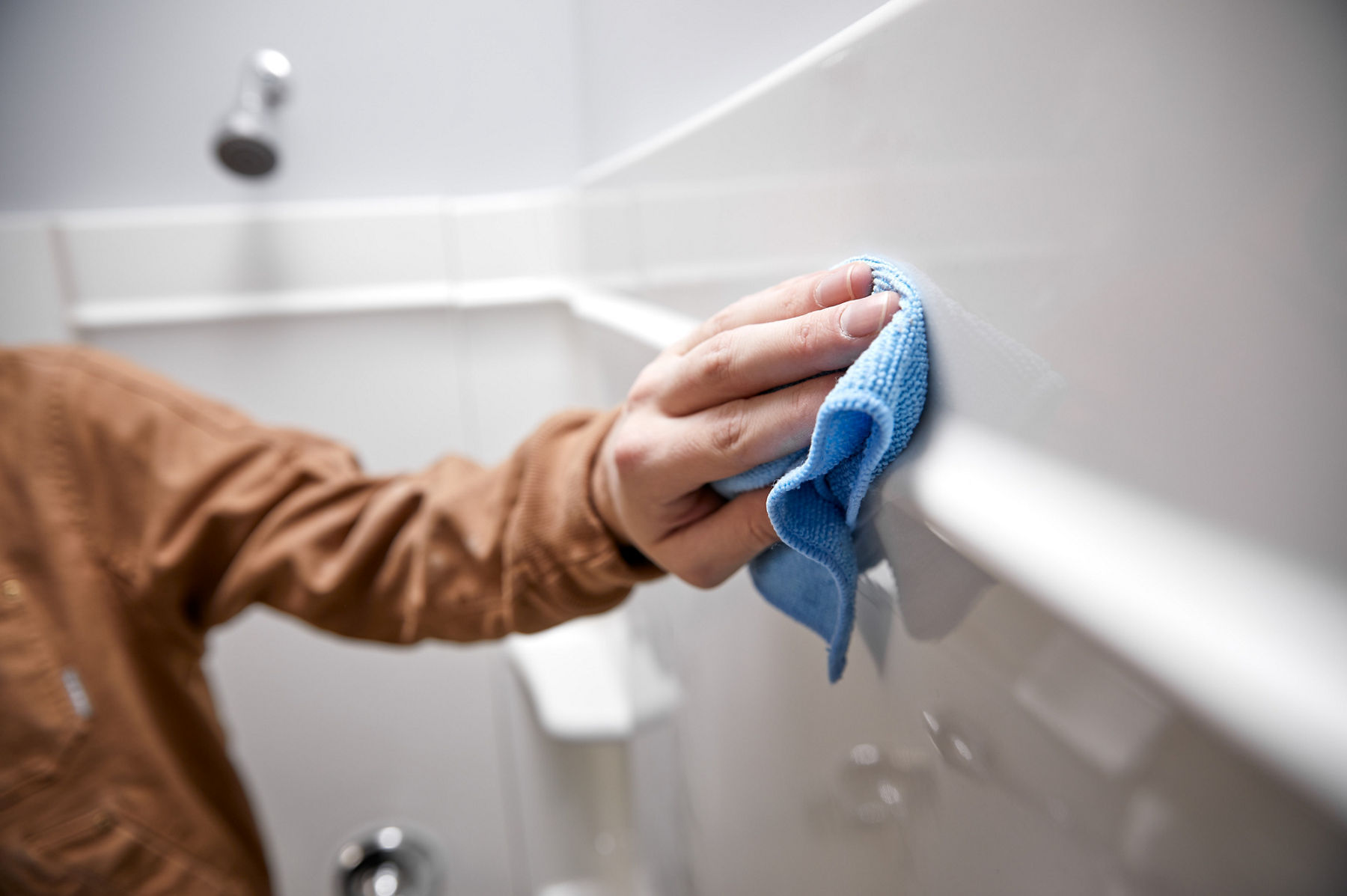 A hand with a microfiber towel wiping down the surface of a Vikrell wall.