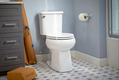 A white toilet against a blue wall with tile flooring.