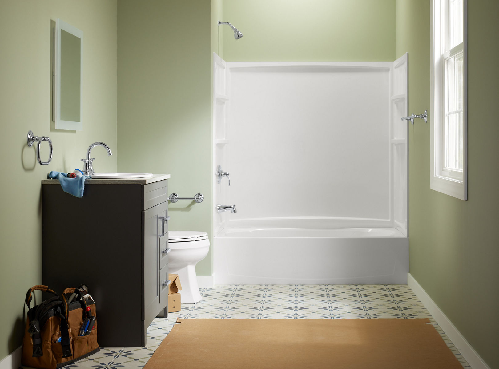A white bathtub with white shower surround in a room with light green walls and tile flooring.