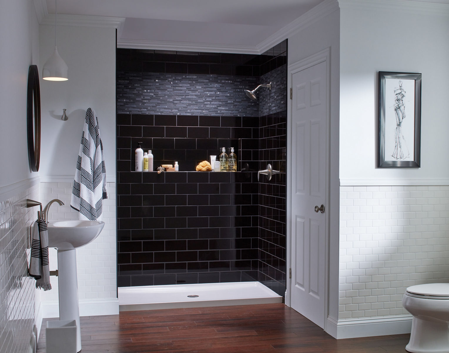 A white shower base and black tile walls.