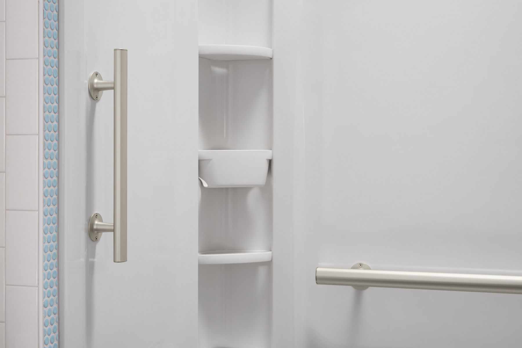 A white shower area with vertical and horizontal grab bars.