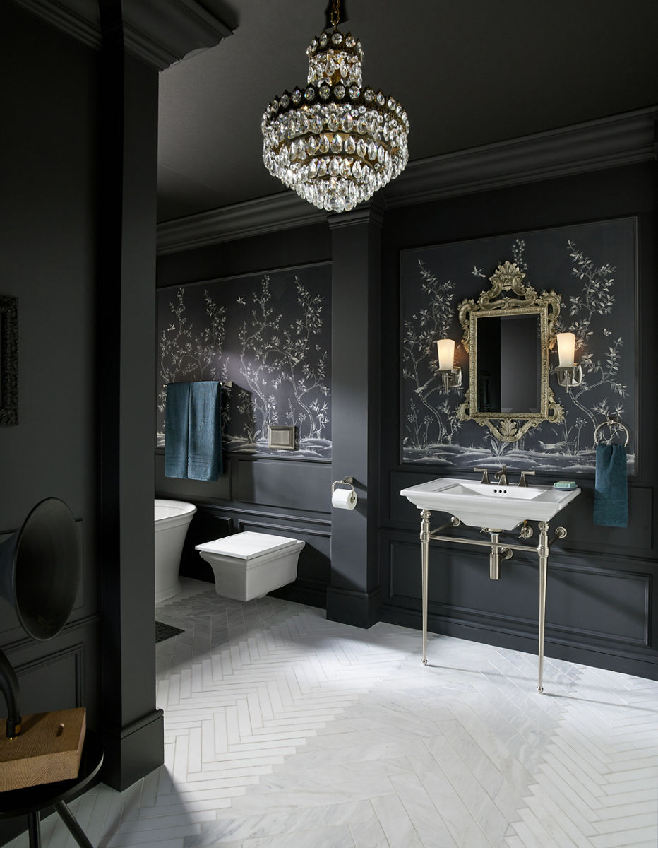 Un lavabo de table console, une toilette et une baignoire autoportante Memoirs dans une salle de bain avec des murs gris foncé ornés de dessins de plantes blanches et d’un miroir orné d’un cadre doré.