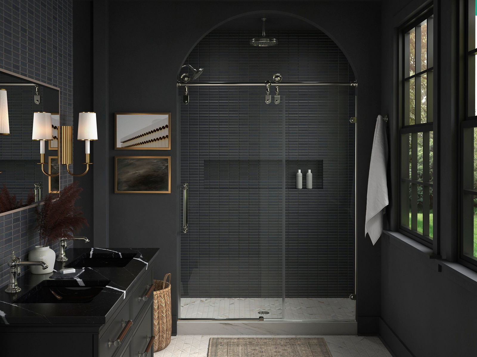 A bathroom with dark gray tile walls, a double vanity with a black counter top and a shower area sharing a combination of polished chrome and brushed brass finishes.