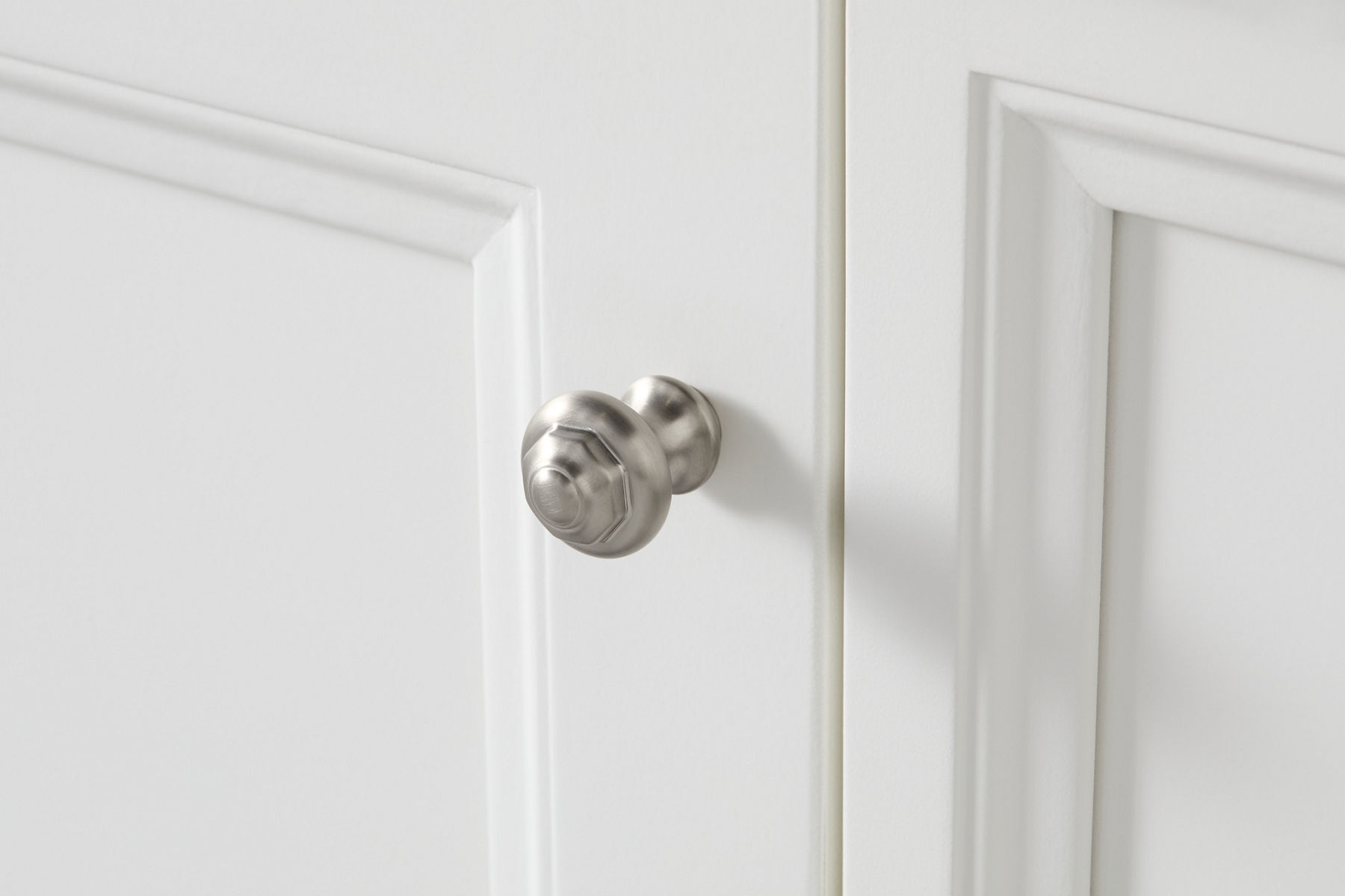 Un bouton d’armoire Artifacts de KOHLER sur une porte de meuble-lavabo blanche.