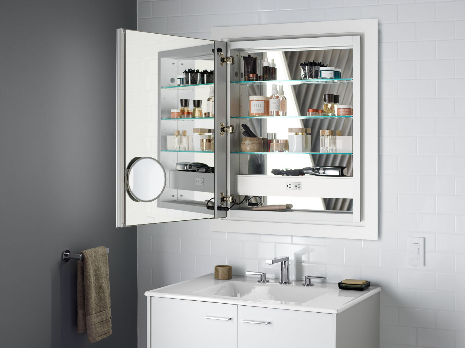 Une armoire à pharmacie ouverte KOHLER révèle les caractéristiques offertes en option, notamment un intérieur miroir et un miroir grossissant réglable.