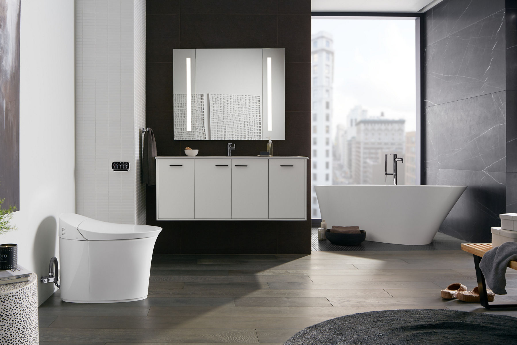 A lighted mirror against a black wall over a white vanity with a chrome faucet.