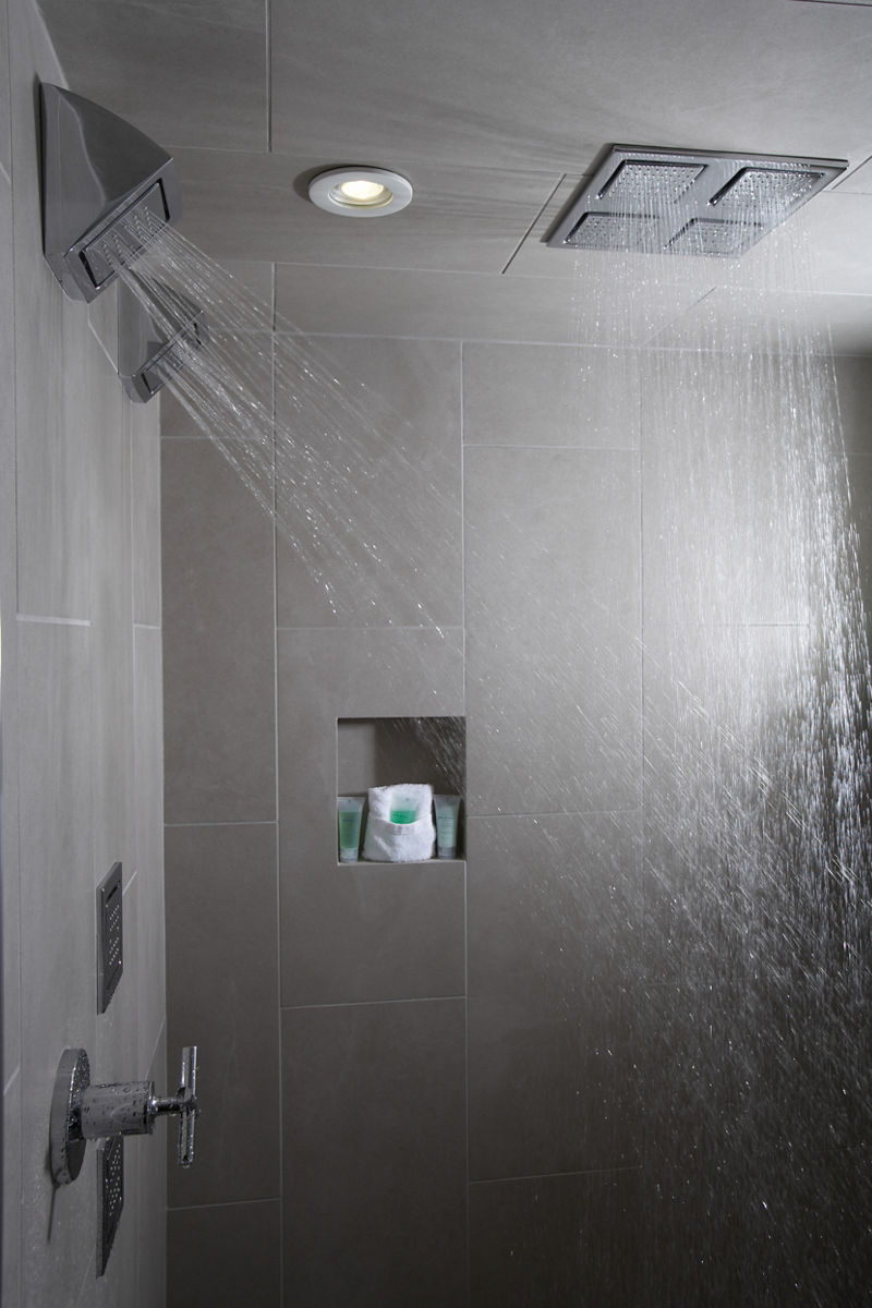 Action shot of Kohler WaterTile® body sprays in Polished Chrome showering water from top and side angles.