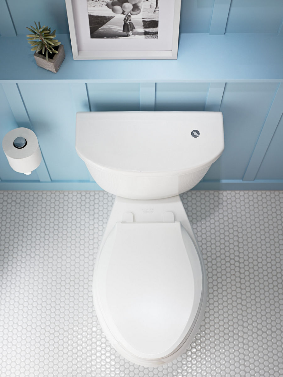 Toilette allongée blanche avec couvercle fermé installé contre un lambris bleu clair