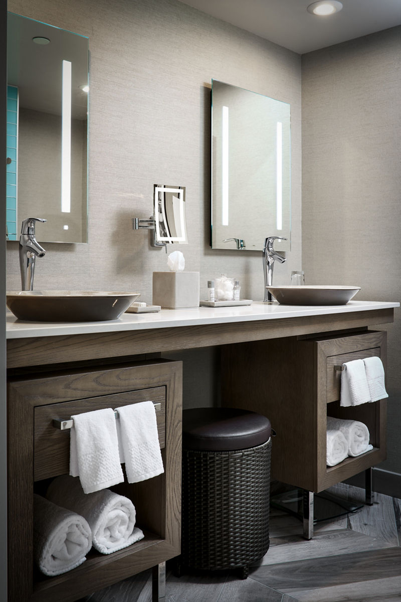 Photo of double vanity with two vessel sink paired tall bathroom sink faucets under two illuminated bathroom mirrors.