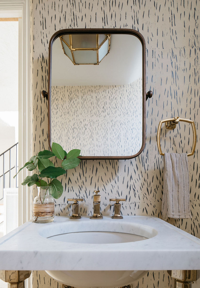 Une table console blanche Kathryn de KOHLER avec lavabo rond blanc, dans une salle de bain avec papier peint à imprimé animalier.