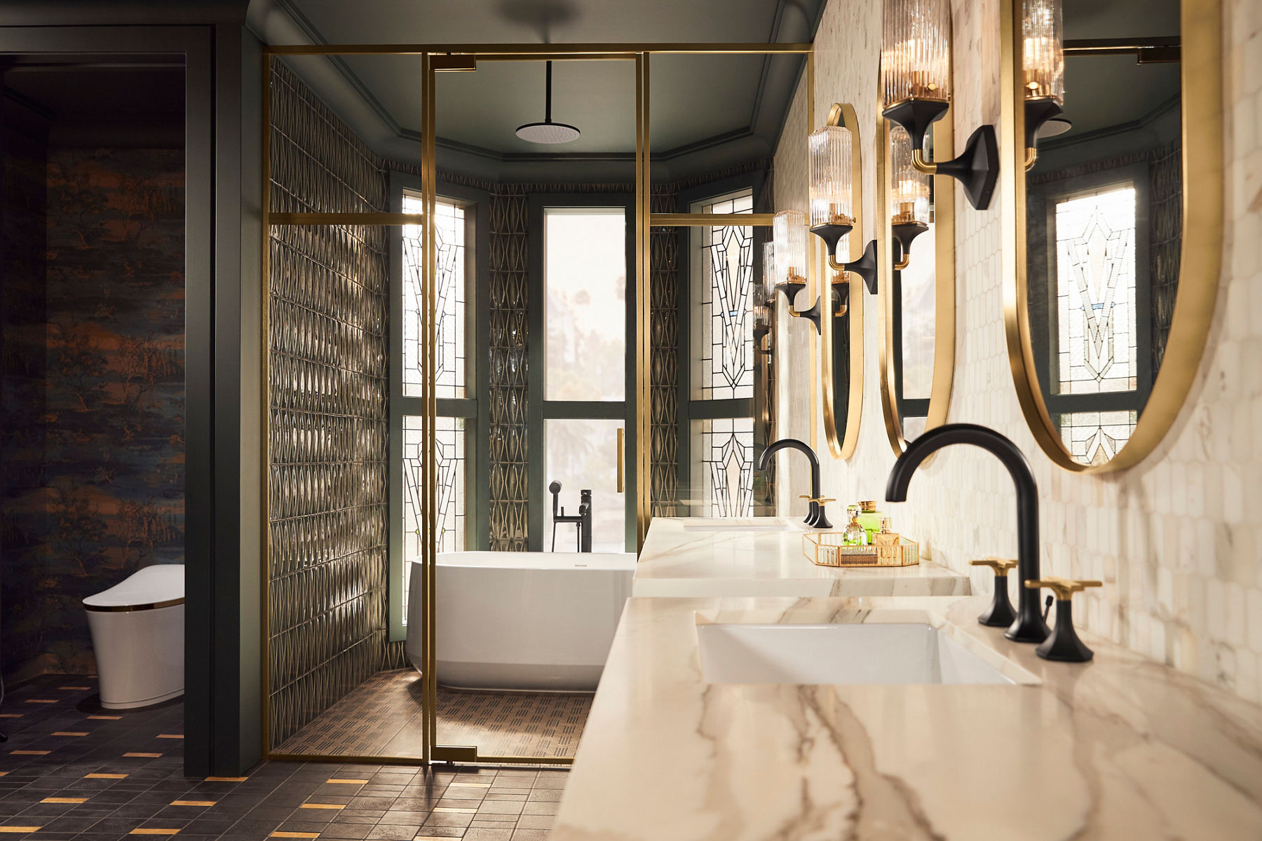 Luxurious bathroom with dual marble sinks, black faucets, and large oval mirrors framed in brass. Wall sconces with textured glass add warm lighting, and a freestanding bathtub is visible near intricate window panels.