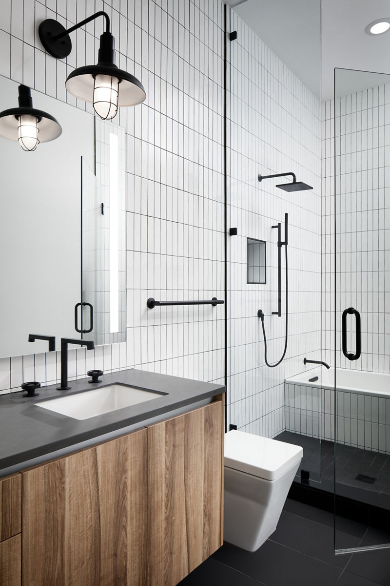 Photo of contemporary bathroom featuring white tiles and wood themed vanity with Kohler fixtures and accents in Matte Black.
