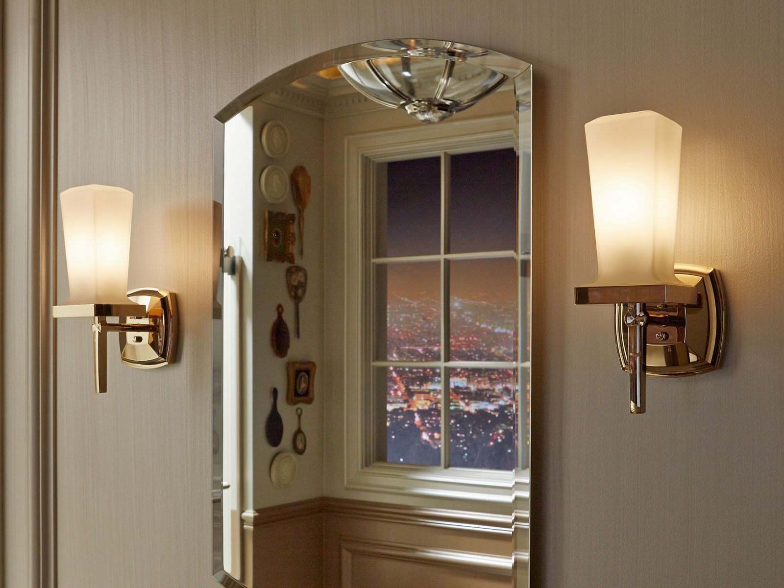 Close up detail of the corner of a beveled medicine cabinet mirror, showing the beveled edge and reflecting a night time city scape seen from an elevated view point.
