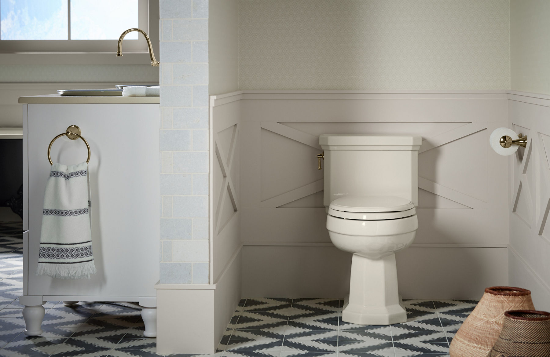 Une toilette blanche Kathryn de KOHLER dans une salle de bain avec un plancher en carrelage à motifs noirs et blancs.