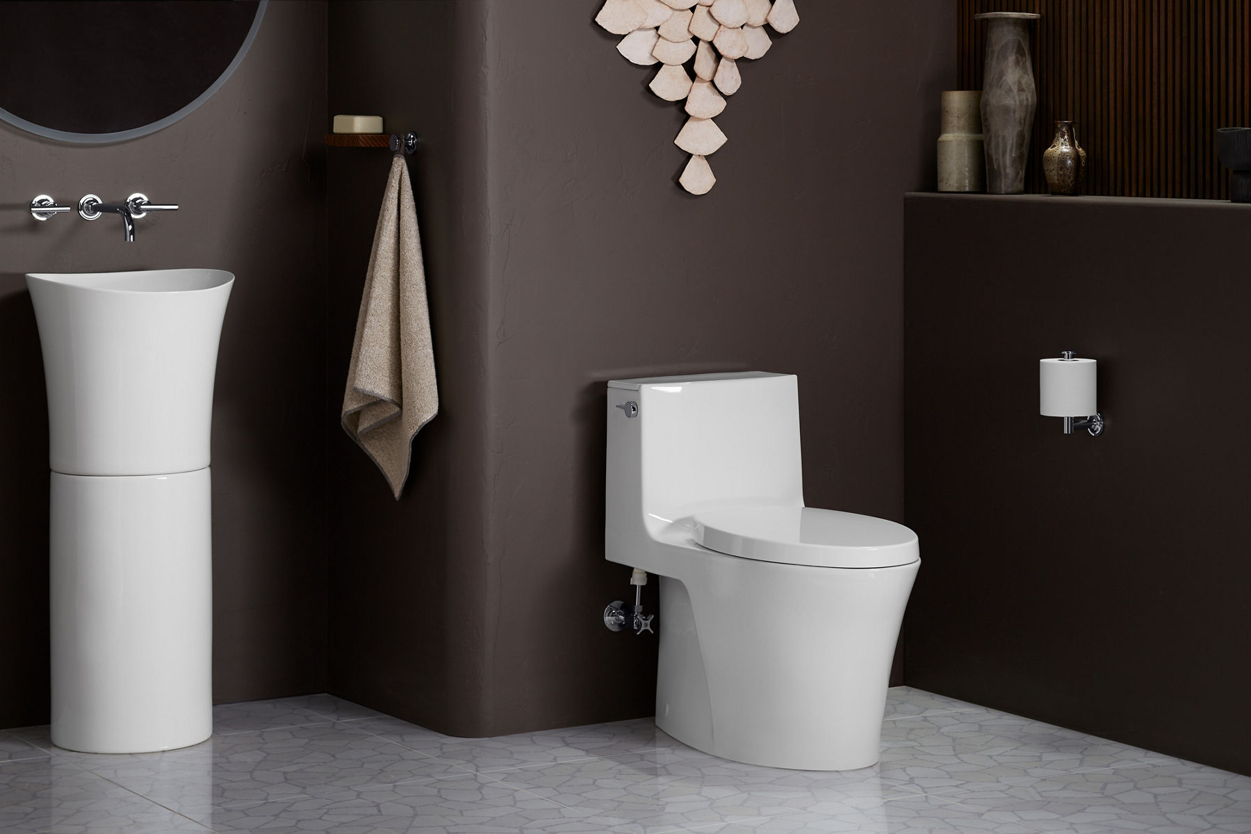 Une toilette allongée monopièce compacte blanche Veil de KOHLER installée dans une salle de bain brune.