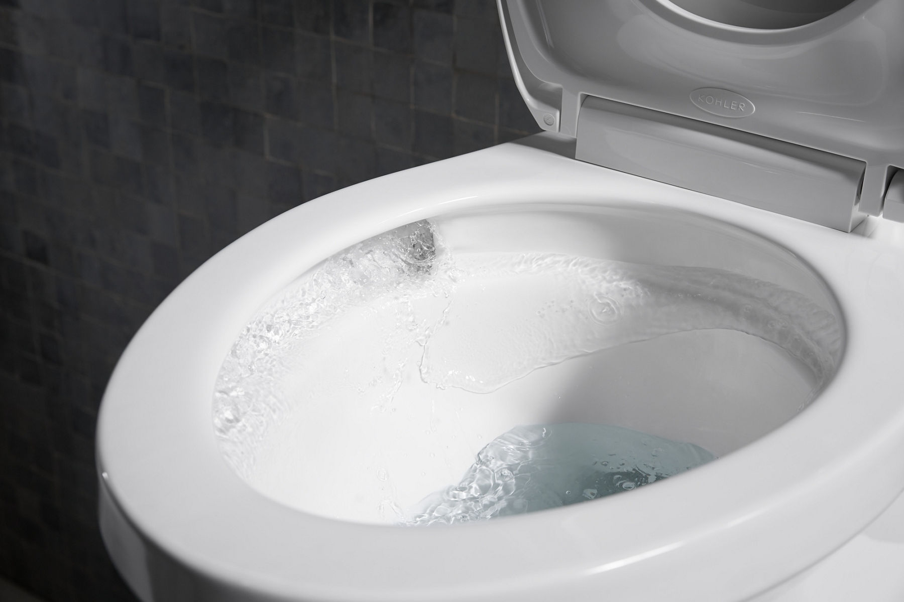 A white KOHLER Corbelle toilet, open with water swirling in 360 degrees around the entire bowl.