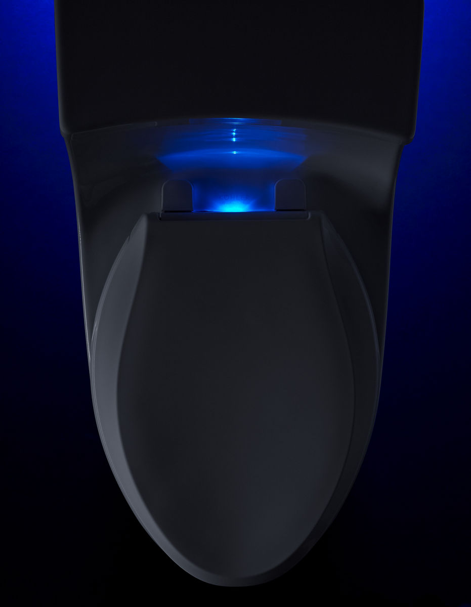 Une toilette blanche équipée d’un siège de toilette éclairé s’illumine en bleu dans le noir.