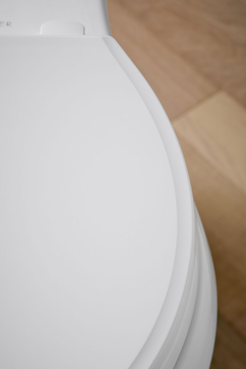 Vue latérale d’un siège de toilette blanc fermé.