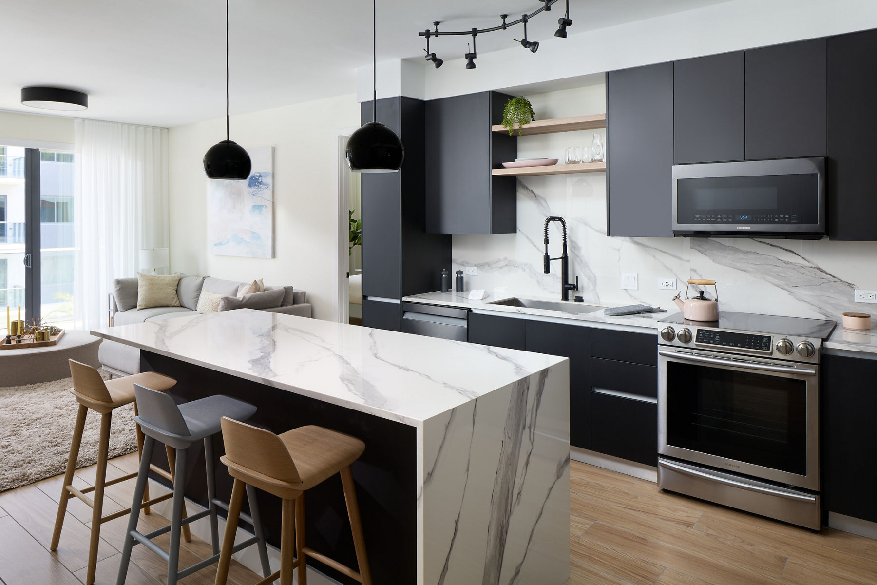 Photo of apartment with modern renovations including marbled kitchen island with matching backsplash in daylight