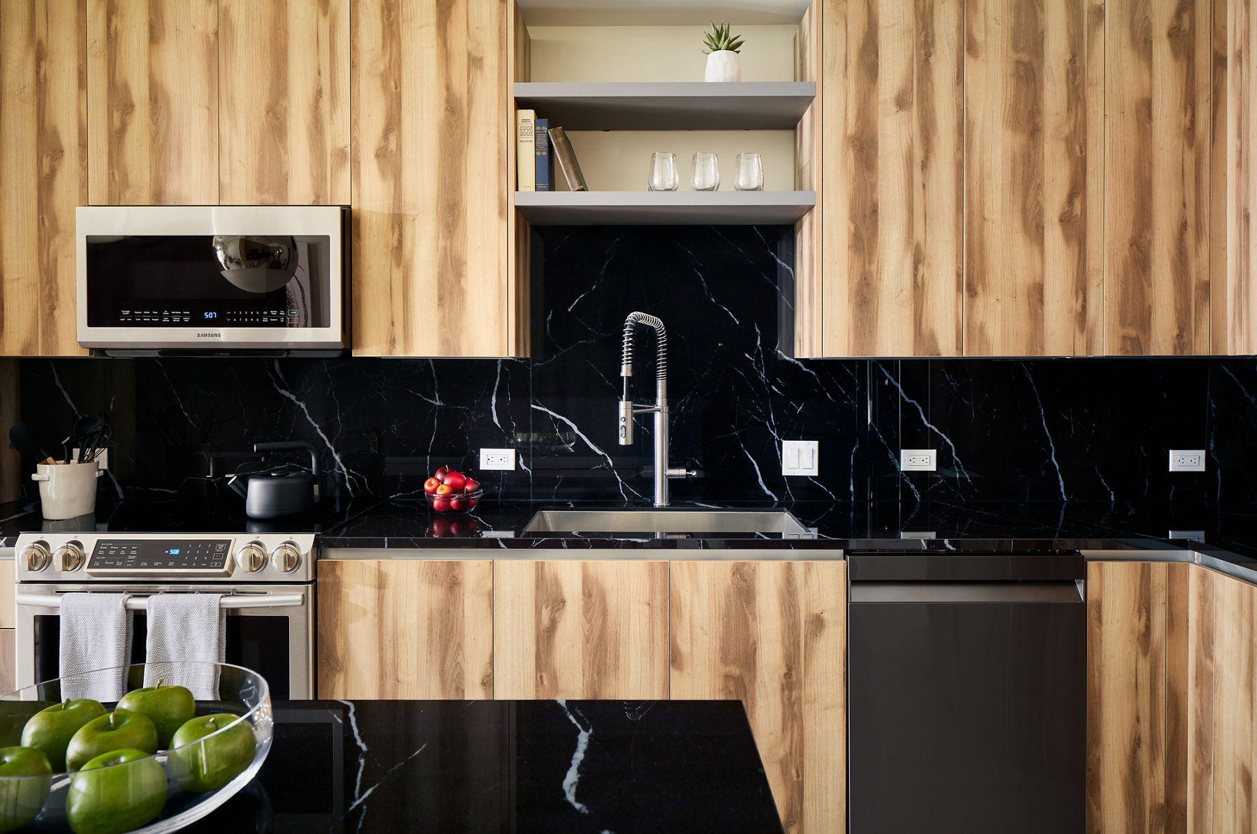 Image of modern kitchen with wood themed cabinetry in daylight.