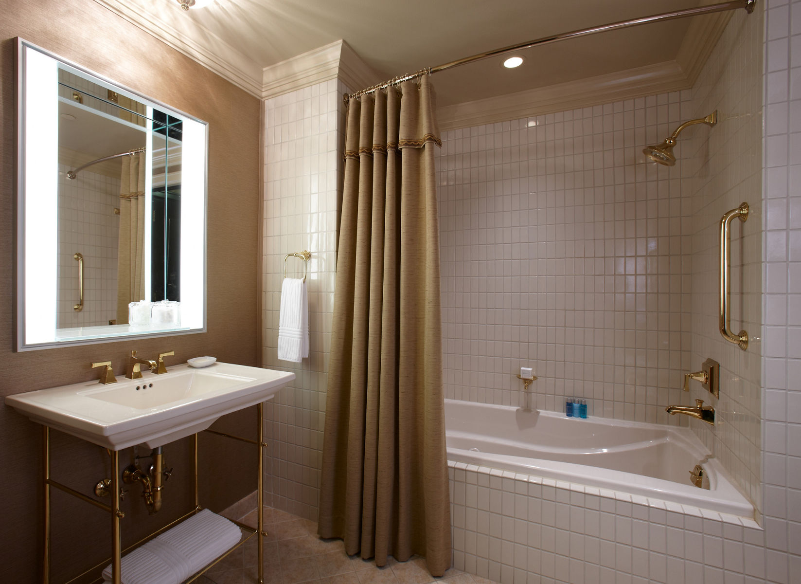 A dimly lit bathroom with luminated vanity mirror above a bathroom sink.