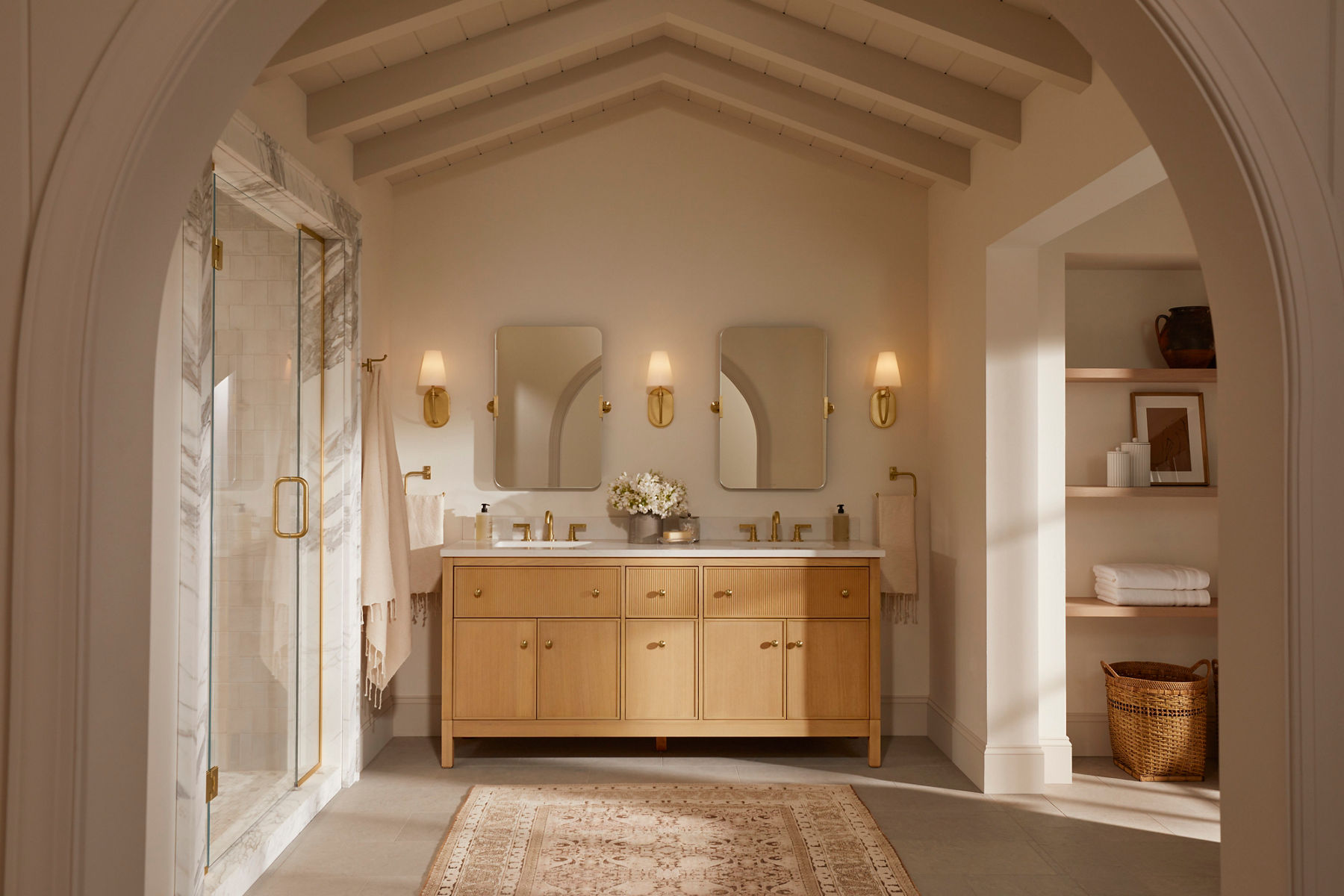 Une salle de bain aux tons neutres en bois beige et clair avec un meuble-lavabo double au centre conçu par Shea McGee.