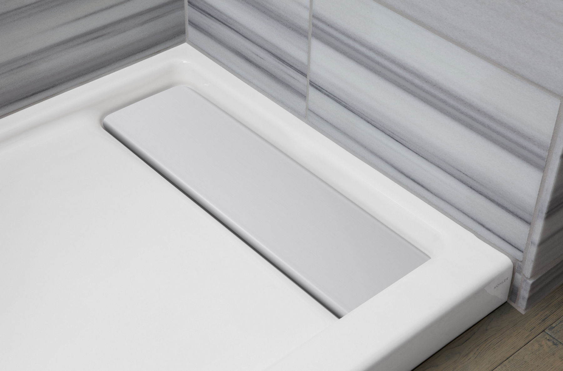 Panneau de douche avec drain encastré à droite et couvercle de drain en aluminium.