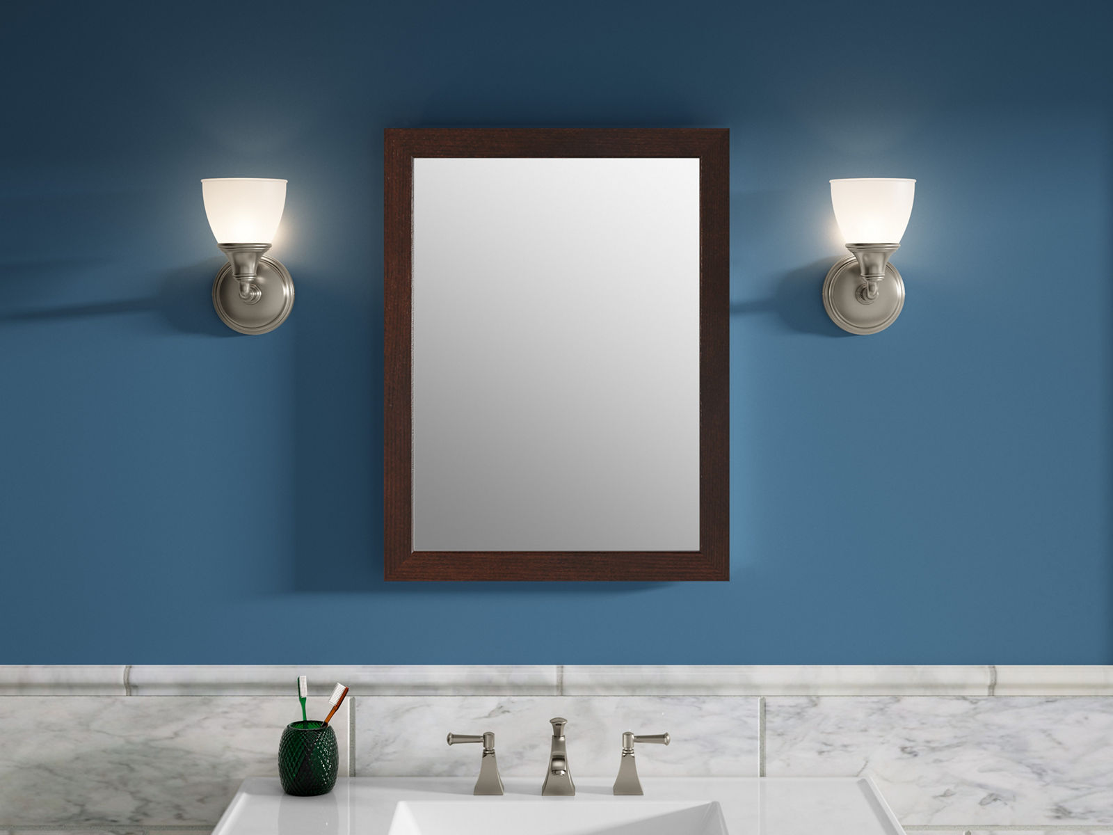 Un miroir avec cadre Tresham de KOHLER en bois est suspendu entre deux appliques contre un mur de salle de bain bleu, au-dessus d’un meuble-lavabo blanc et d’un lavabo.