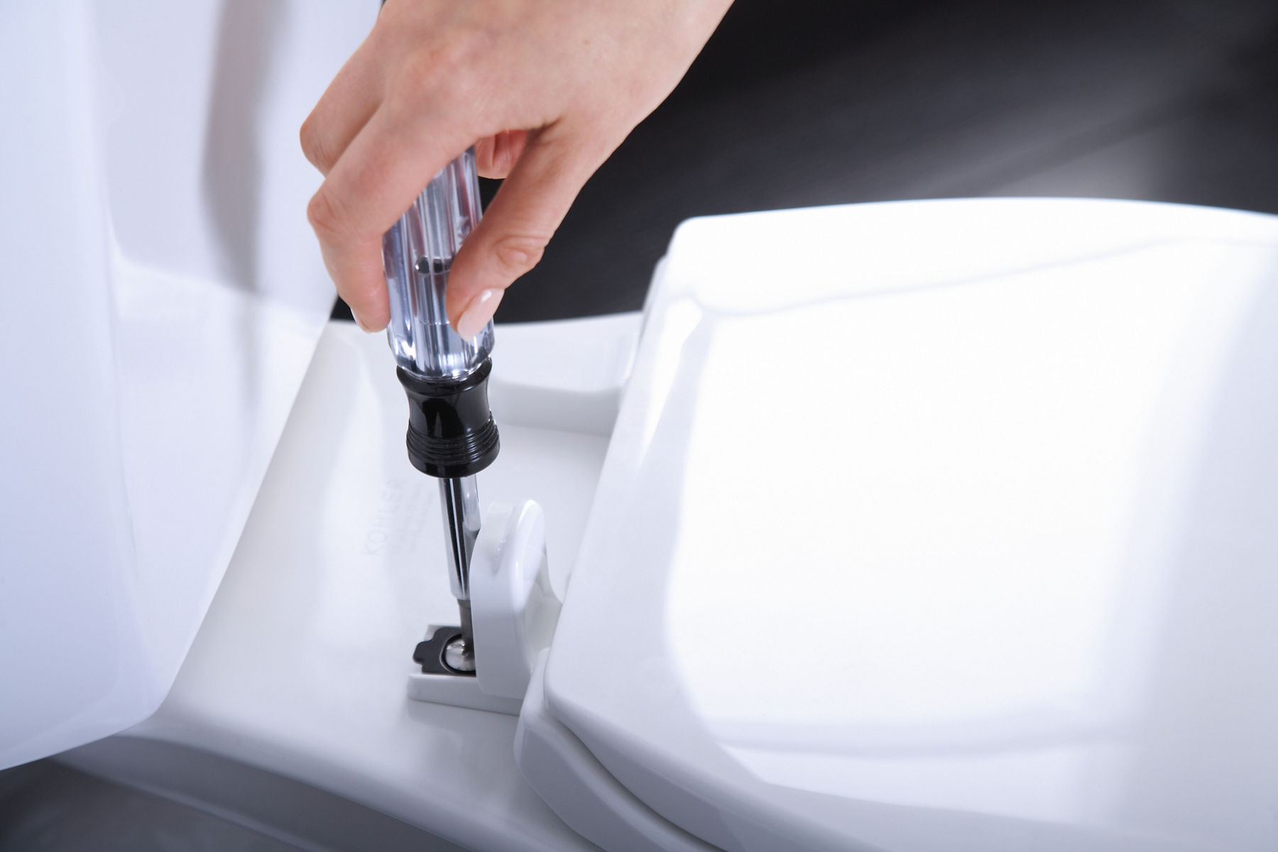 Une personne utilise un tournevis pour installer un siège de toilette KOHLER Brevia.