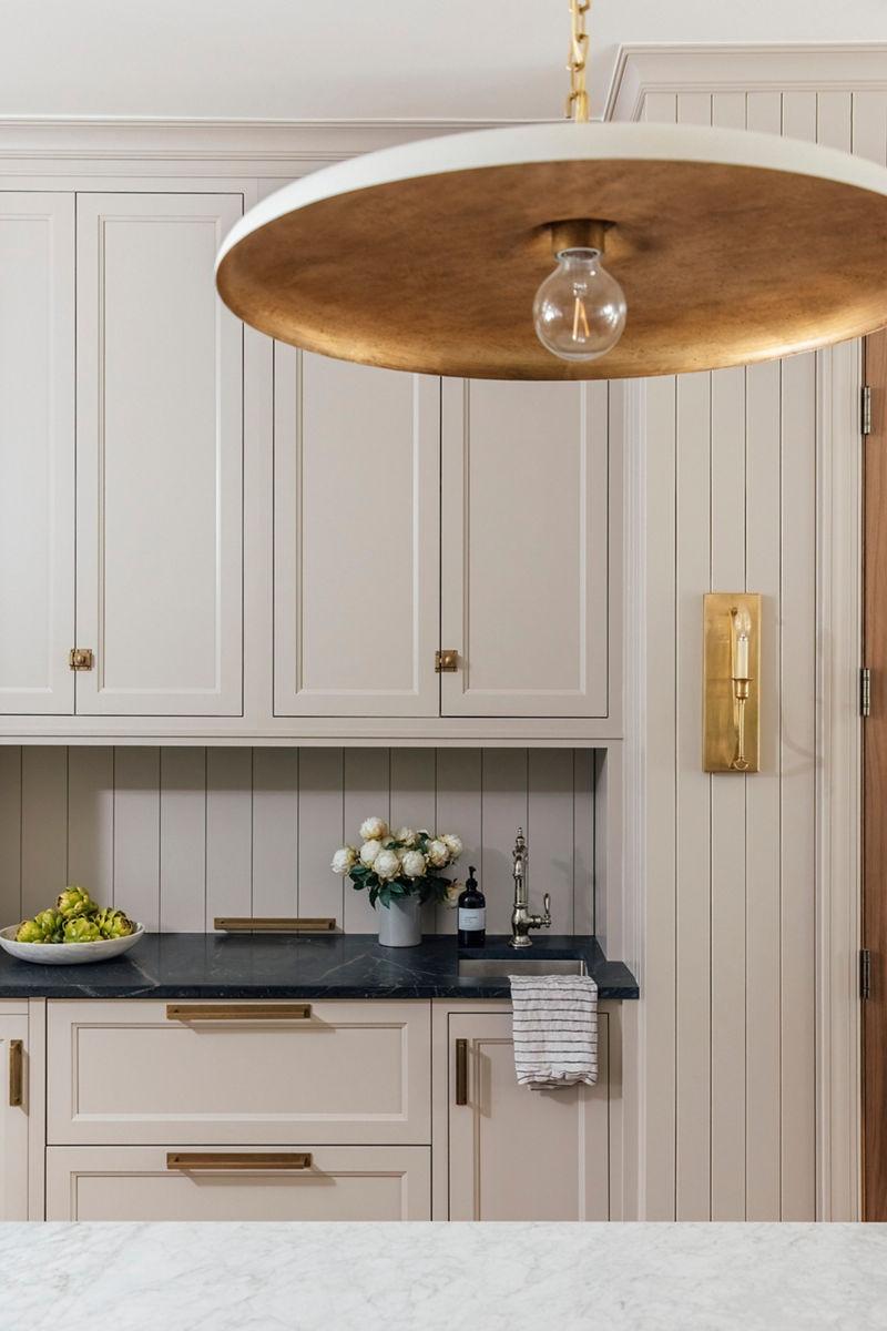 Close up image from Chris and Julia's kitchen of the cream-colored back-wall cabinets and stone counter top where a Kohler bar sink is installed with a polished nickel Kohler Artifacts Gentlemen's bar faucet.