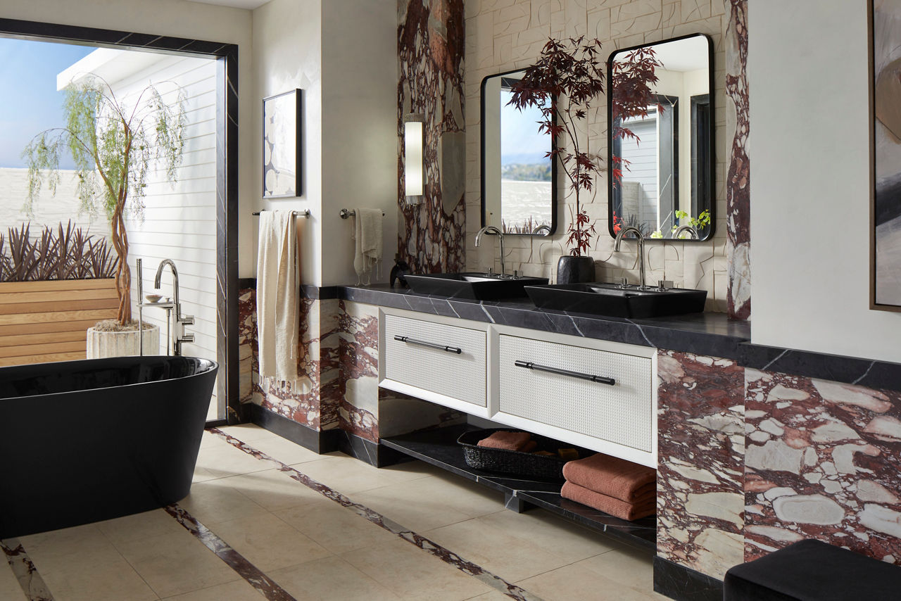 A bathroom with a double floating white vanity with matte black sinks and a matching freestanding bath in front of an open patio door.