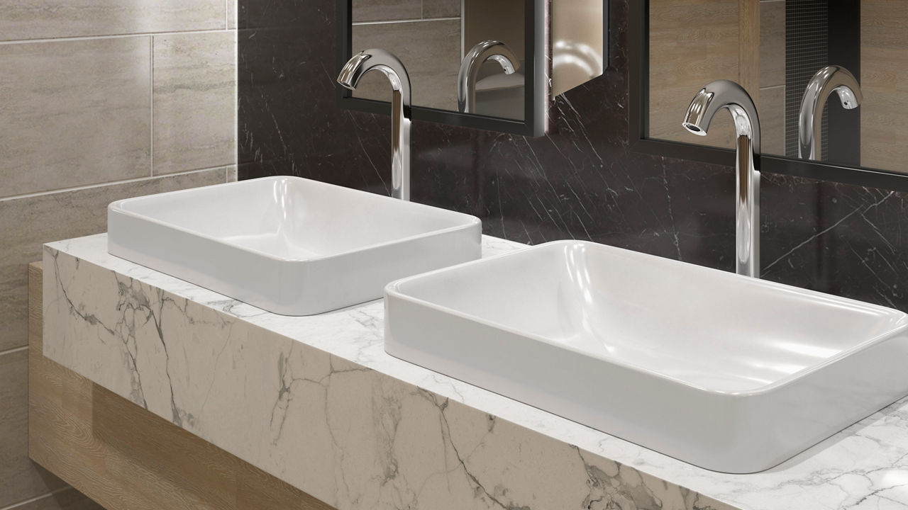 A white KOHLER rectangle vessel sink with a tall, arched touchless faucet in a bathroom with black marble backsplash.
