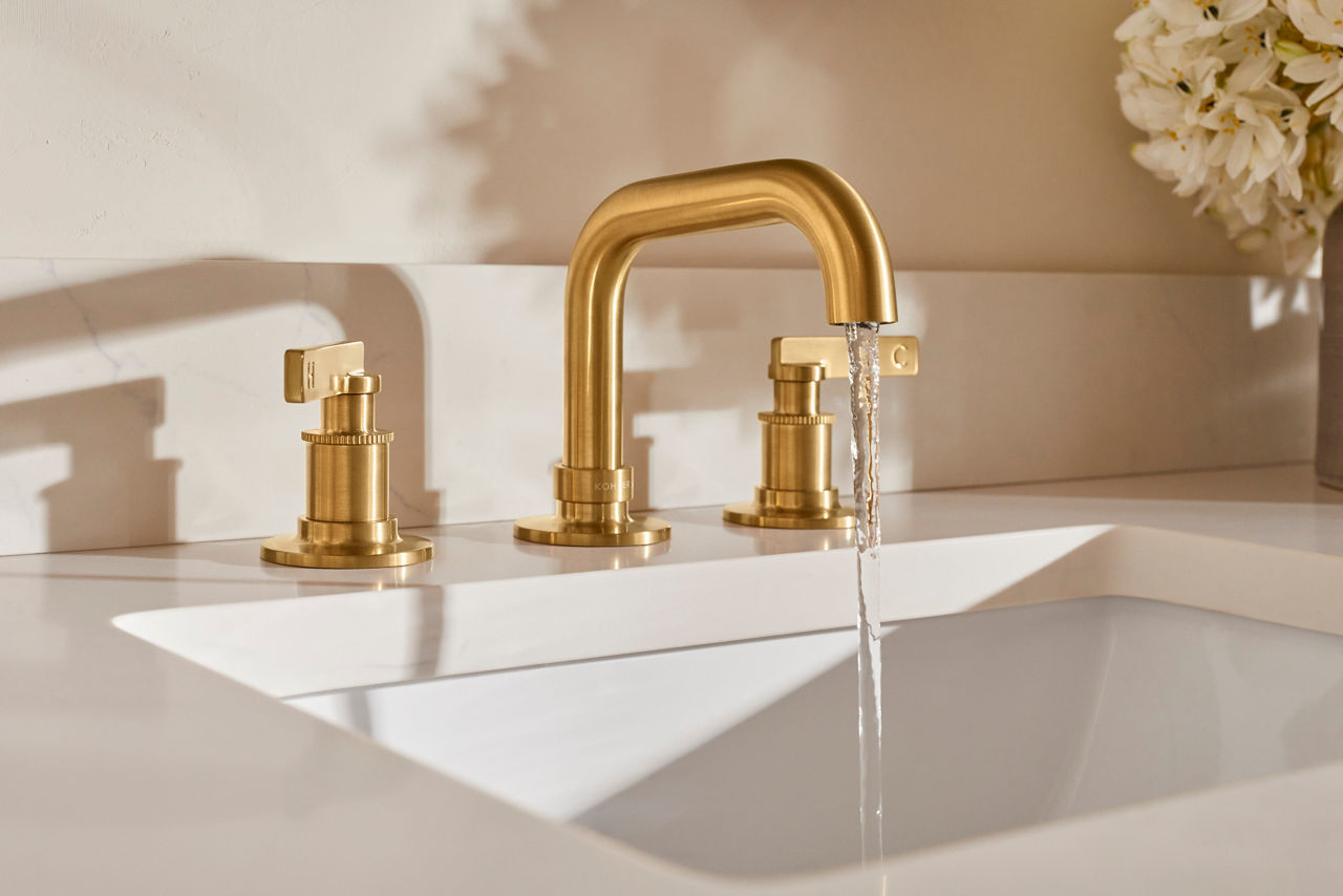 Close up of a brushed brass faucet designed by Shea McGee on a bathroom counter top.
