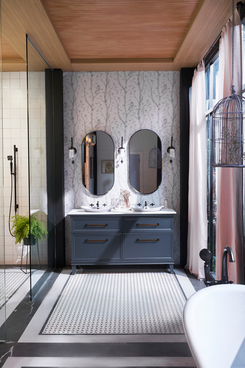 Two oval capsule mirrors hang above a blue KOHLER Harken double vanity with white Great Plains vessel sinks.