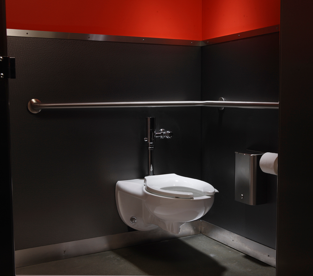 A black bathroom with white KOHLER Kingston wall-mounted toilet with Stronghold toilet seat and a Wave touchless flushometer.
