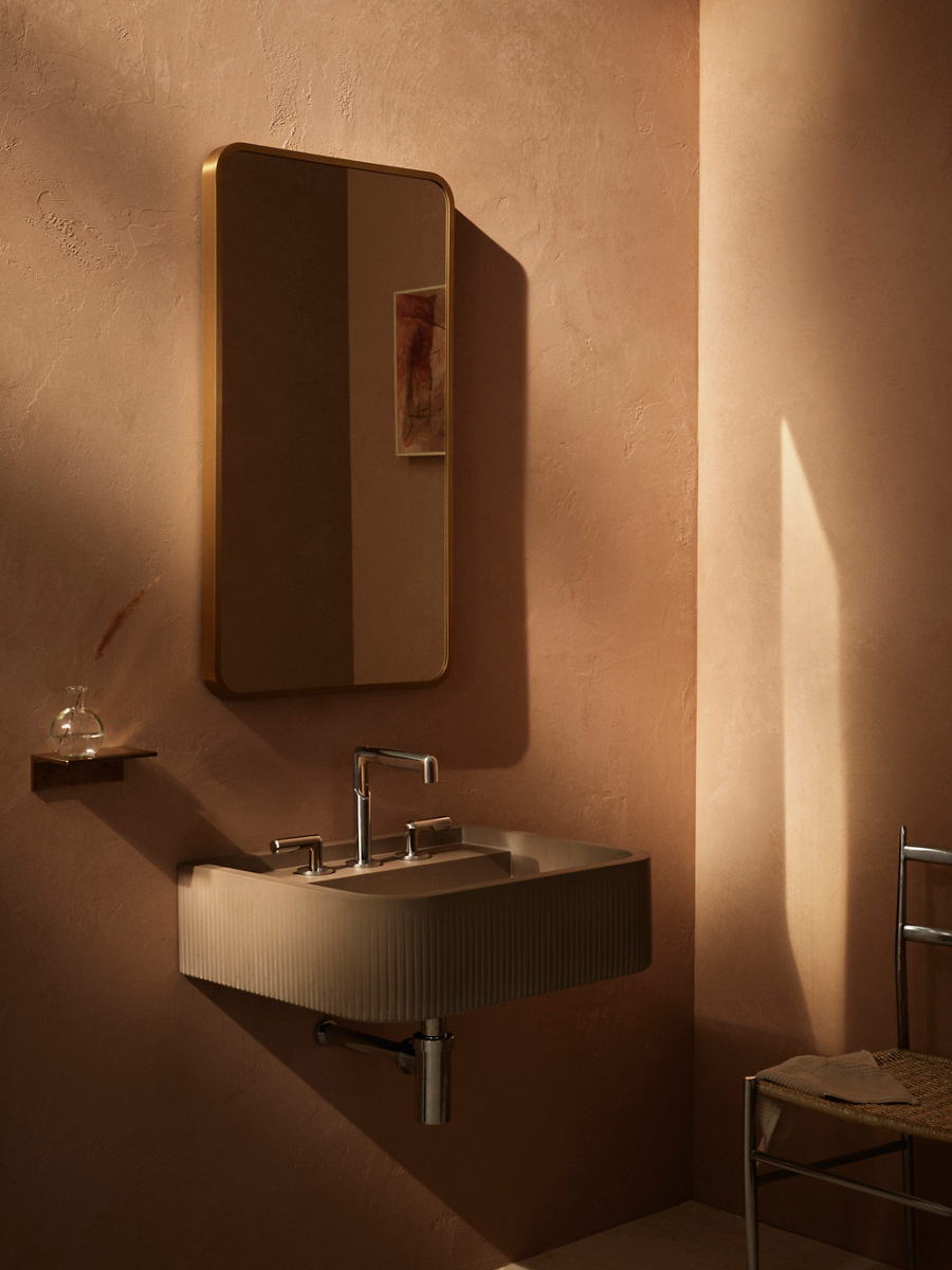 Illuminated mirror above wall-mounted sink with polished faucet